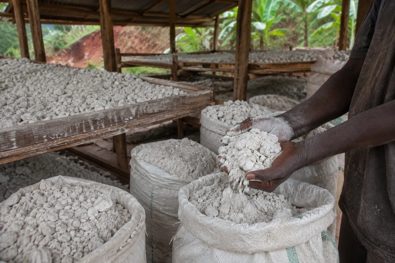 Illustrative visualisation: graded mineral stone being sorted over a screen and bagged under a work shelter