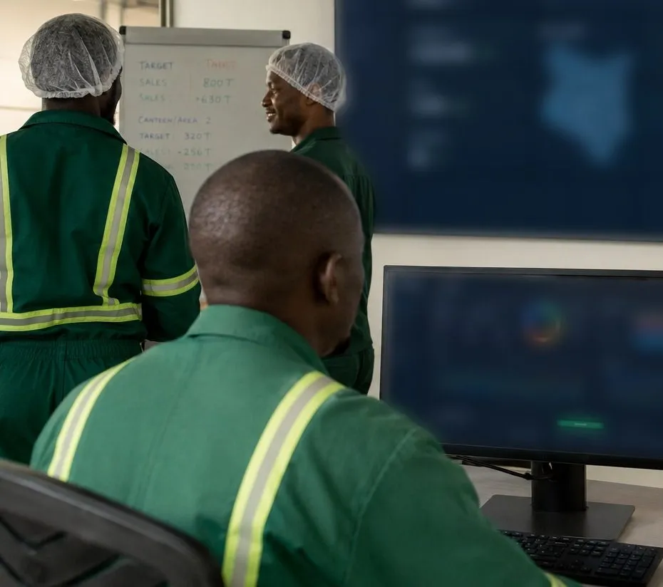 Illustrative visualisation: technicians in processing-floor protective clothing reading quality data on screens