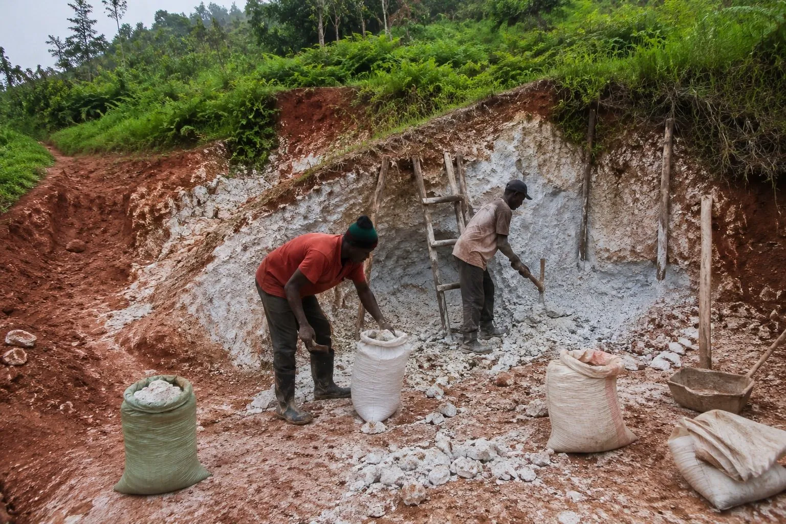 Illustrative visualisation: two workers cutting and bagging stone at an open quarry face cut into a hillside